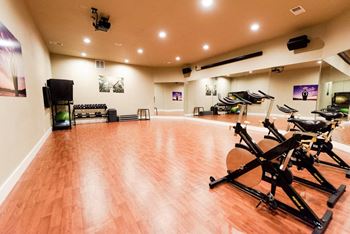 a workout room with a wood floor and exercise bikes